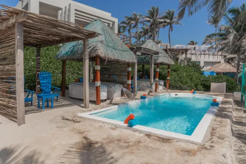 Thatched cabanas beside a small pool on the sand at Grand Oasis Cancun.