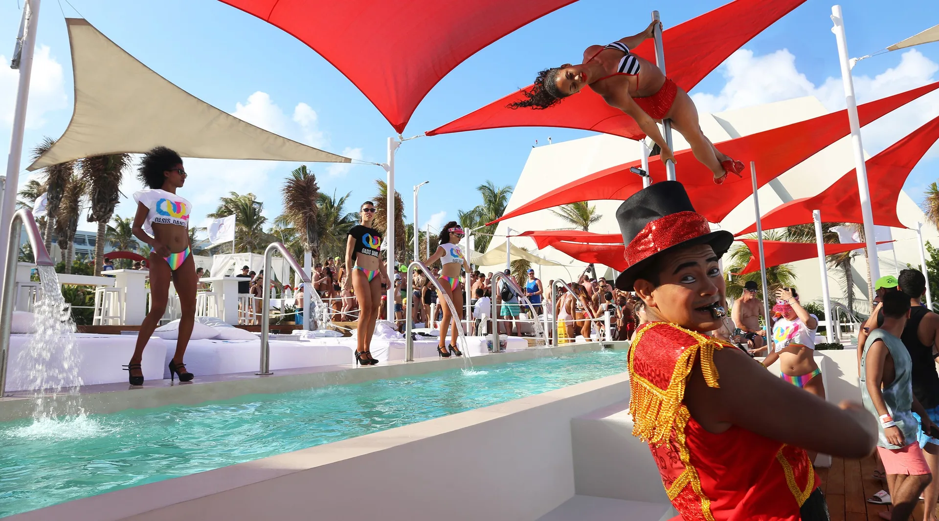 Poolside performers entertain guests beneath red shade sails at Grand Oasis Cancun.