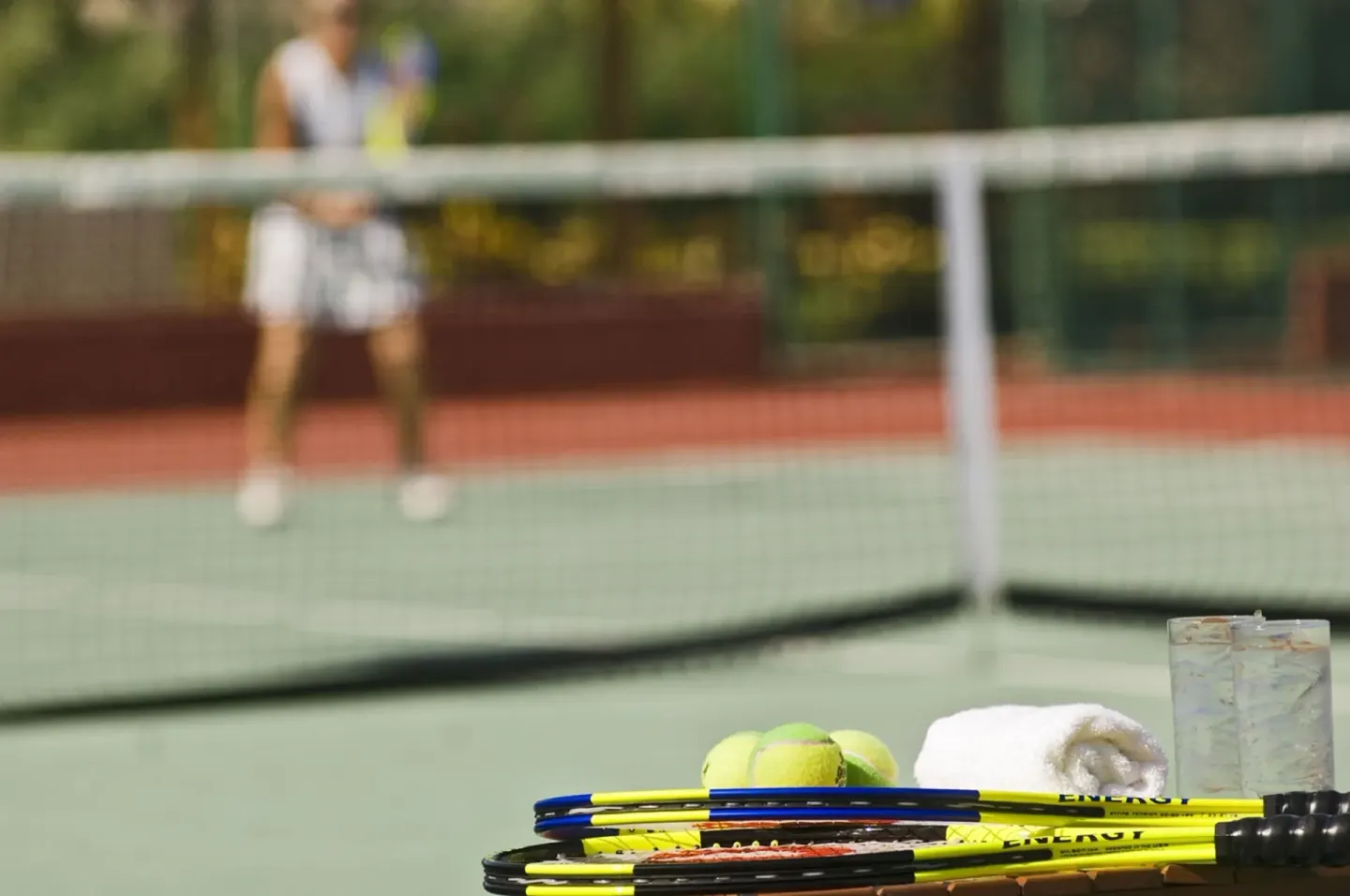 Tennis racquets, balls, towels, and drinks beside a court at Grand Oasis Cancun.
