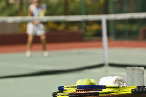 Tennis racquets, balls, towels, and drinks beside a court at Grand Oasis Cancun.