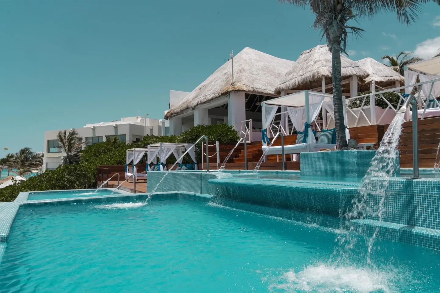 Terraced pool with waterfalls and cabanas near thatched roofs at Grand Oasis Cancun.