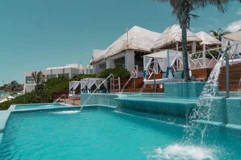 Terraced pool with waterfalls and cabanas near thatched roofs at Grand Oasis Cancun.