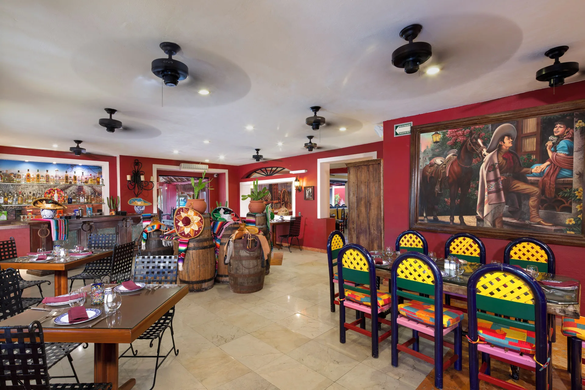 Colorful Mexican-style dining room with painted chairs at Grand Oasis Cancun.