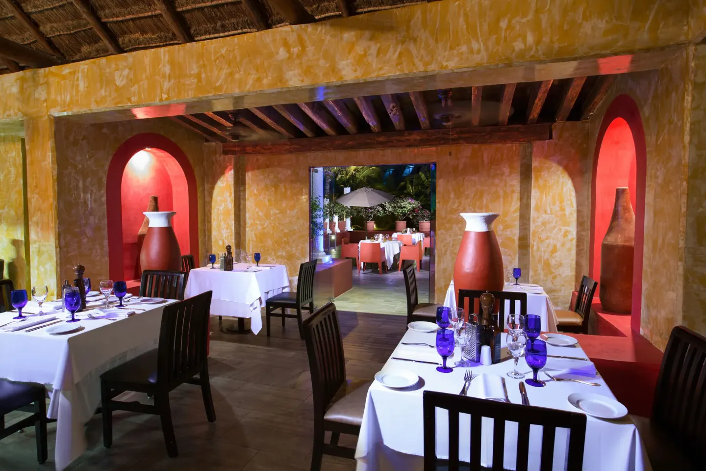 Intimate dining room with blue glassware and alcove vases at Grand Oasis Cancun.