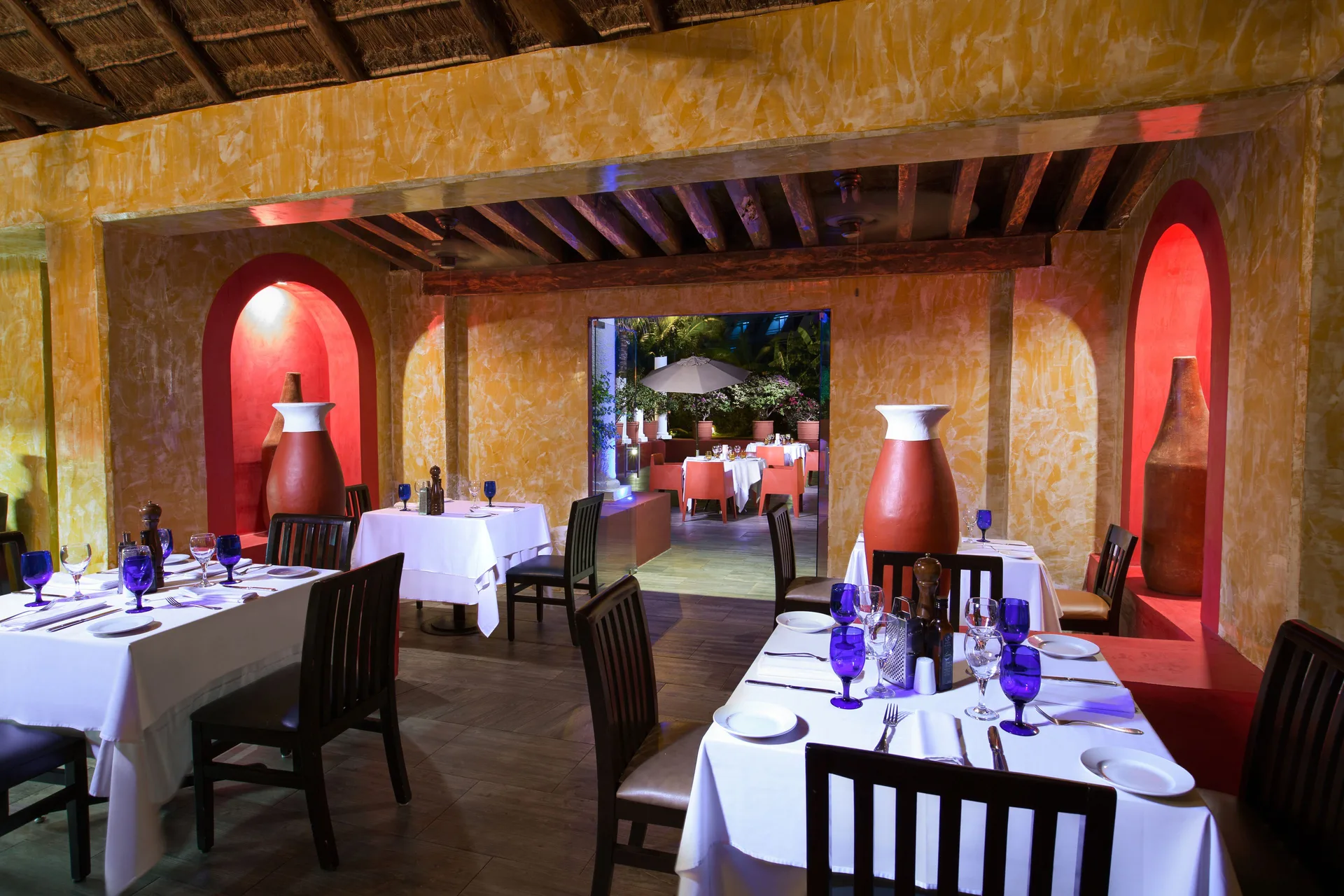 Intimate dining room with blue glassware and alcove vases at Grand Oasis Cancun.