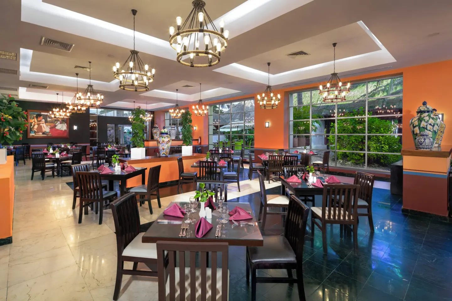 Spacious dining room with chandeliers and orange walls at Grand Oasis Cancun.