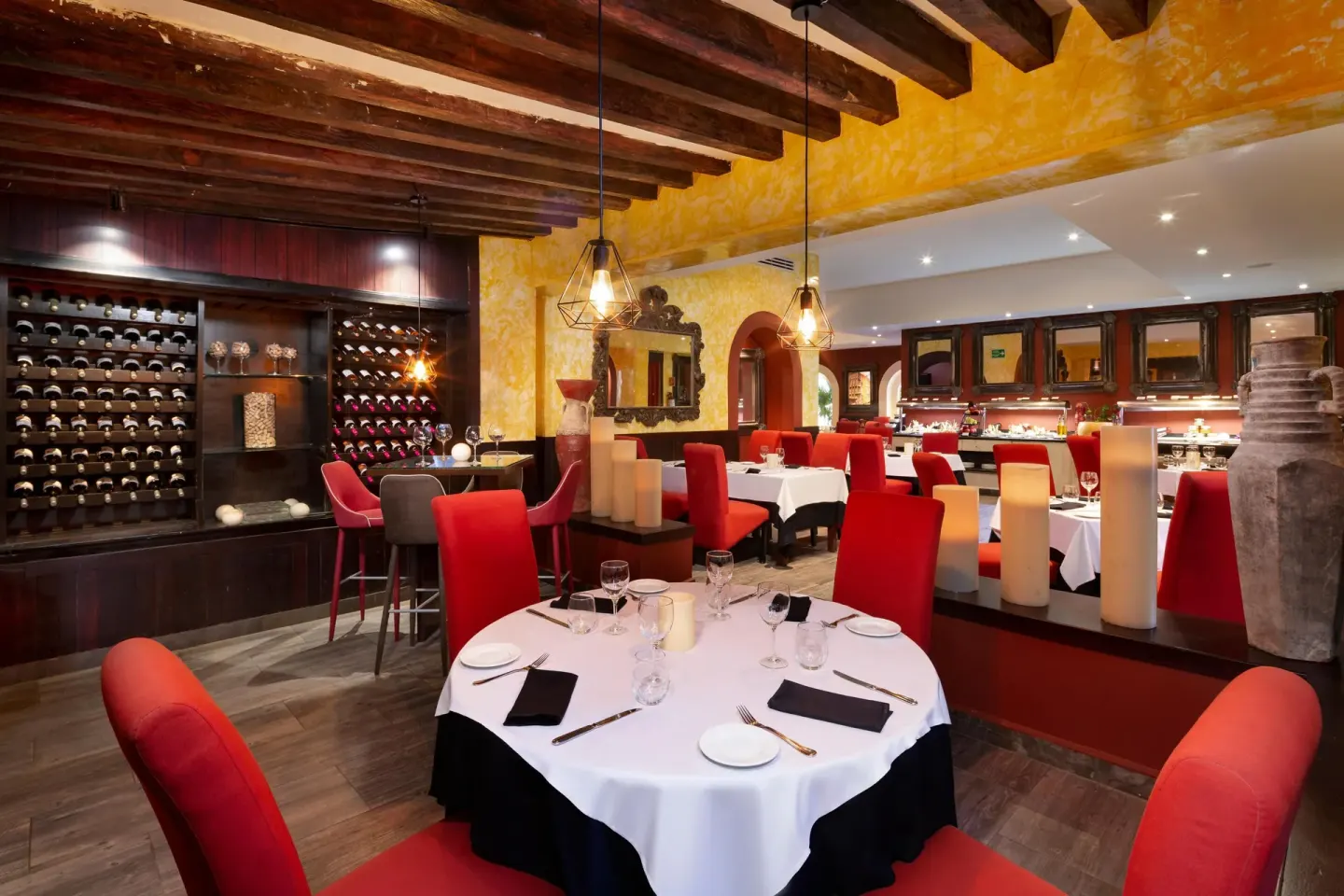 Warm dining room with red chairs and wine displays at Grand Oasis Cancun.