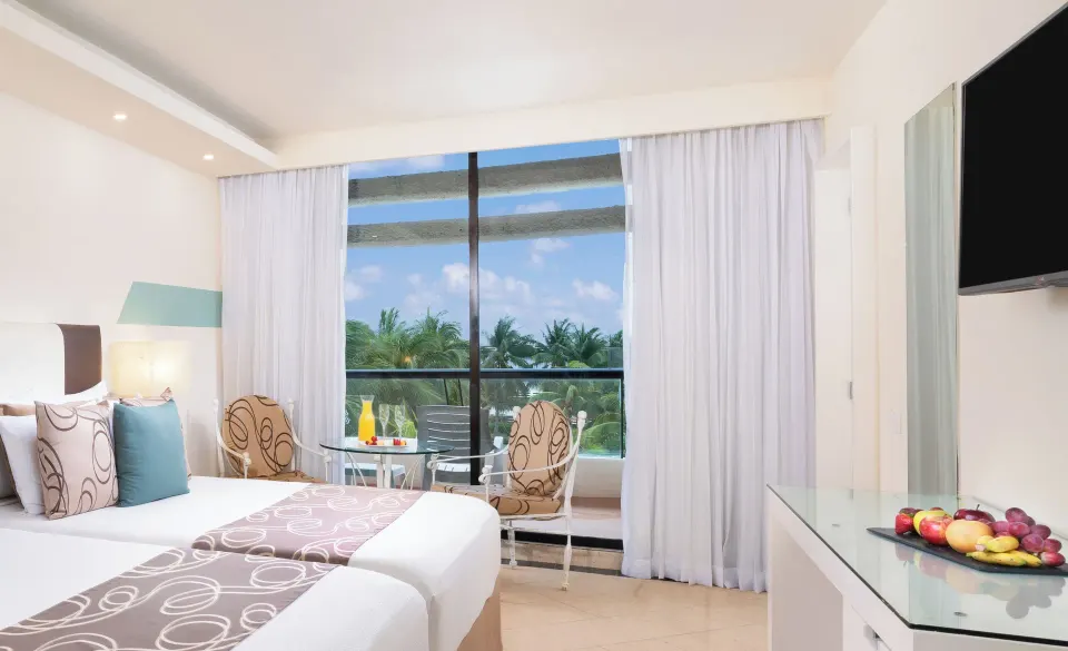 Grand Standard double beds at Grand Oasis Cancun with window seating, TV and fruit tray.