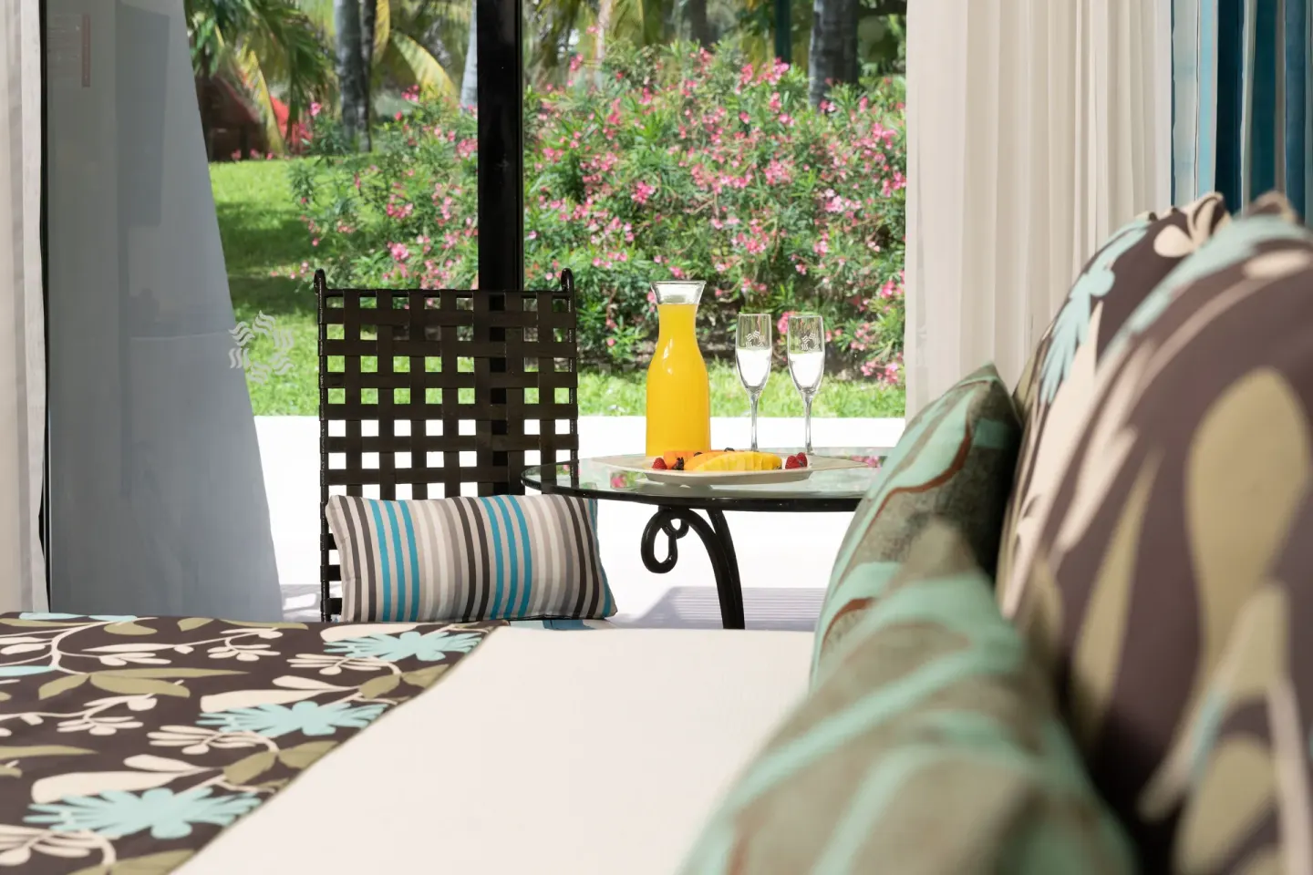 Grand Standard room at Grand Oasis Cancun with bed, terrace table and garden view.