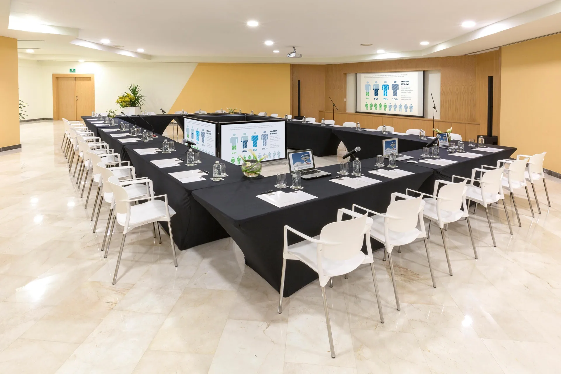 Meeting room with U-shaped tables, white chairs, and screens at Grand Oasis Cancun.