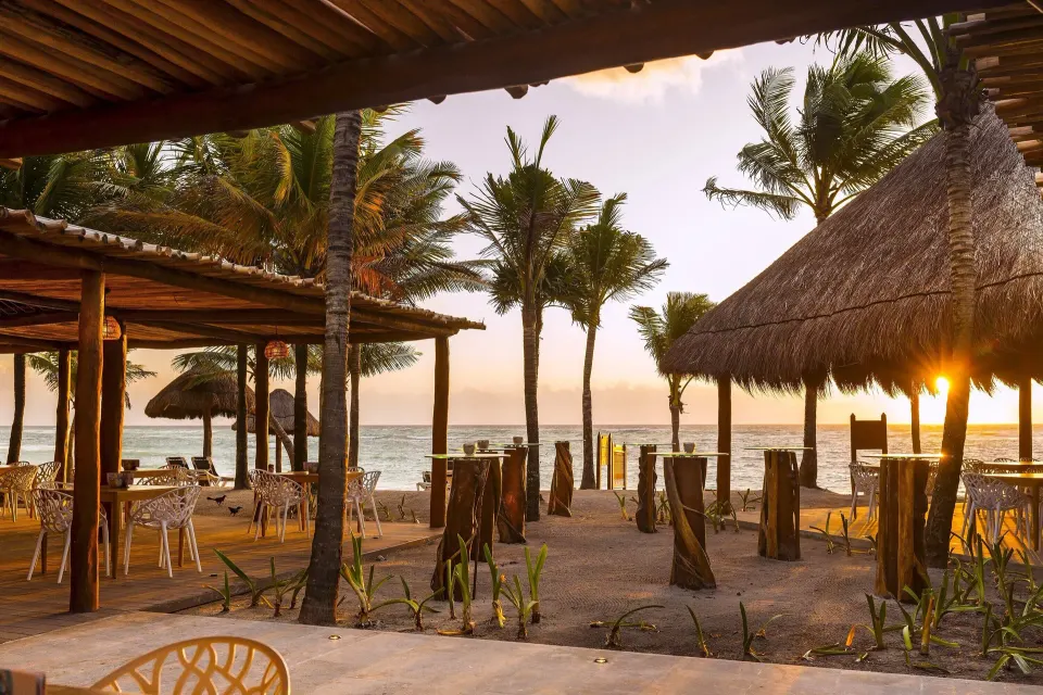 Sunset view of beachfront palapas and seating at Grand Palladium Colonial Resort & Spa