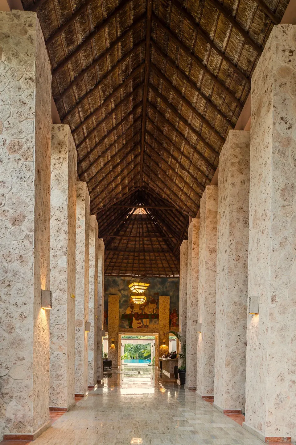 Tall colonnade and palapa roofed lobby corridor at Grand Palladium Colonial Resort & Spa