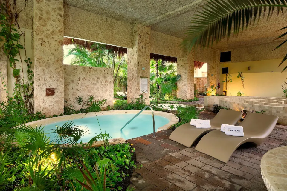 Covered whirlpool and loungers amid tropical foliage at Grand Palladium Colonial Resort & Spa