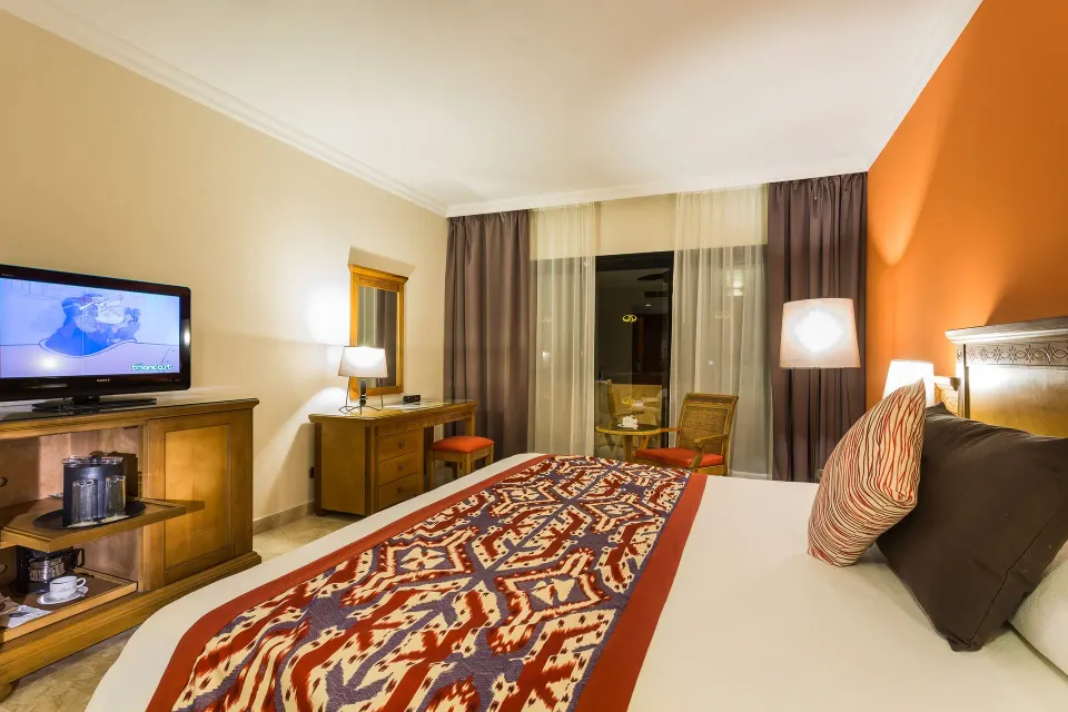 King bed guest room with orange accent wall and balcony at Grand Palladium Colonial Resort & Spa