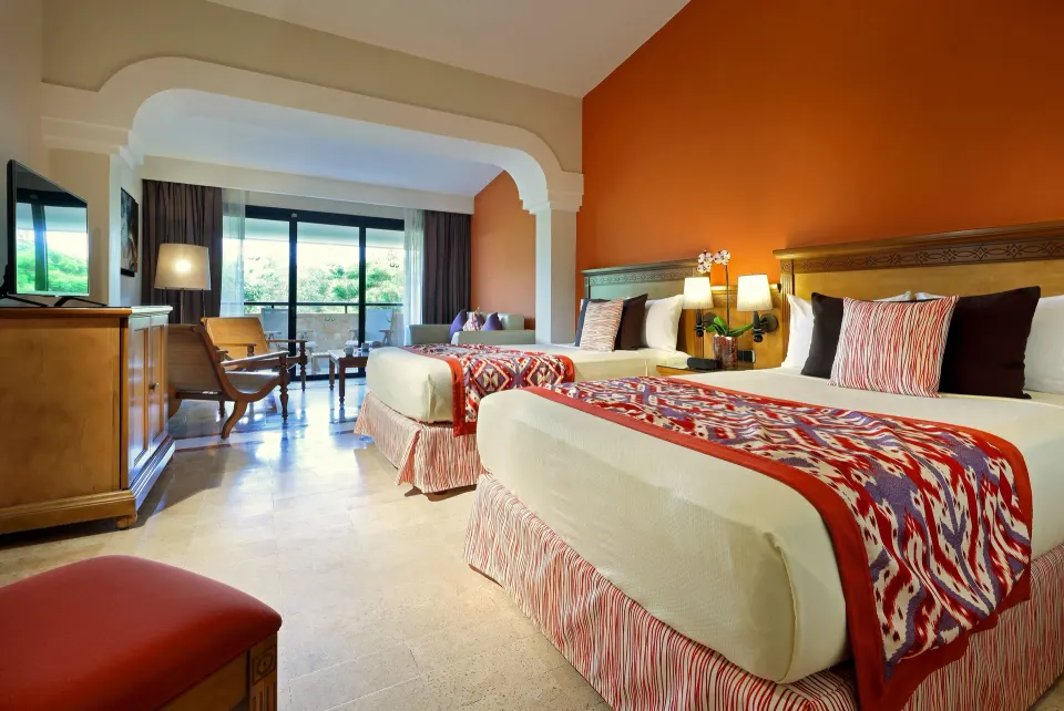 Twin-bedded room with view toward balcony and seating area at Grand Palladium Colonial Resort & Spa