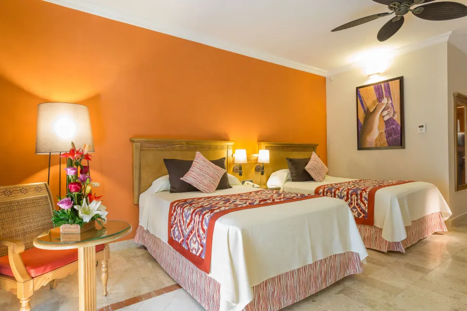 Twin-bedded guest room with warm accent wall at Grand Palladium Colonial Resort & Spa