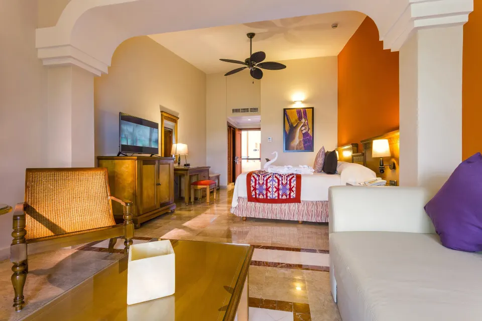 View through arch to king bed and living area in suite at Grand Palladium Colonial Resort & Spa