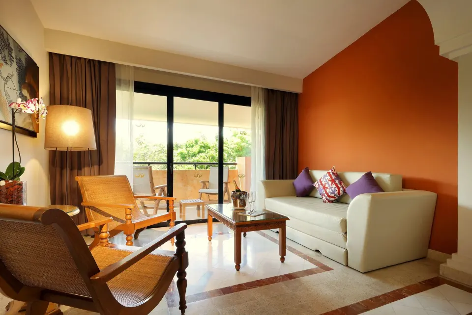 Seating area and balcony doors with greenery view in suite at Grand Palladium Colonial Resort & Spa