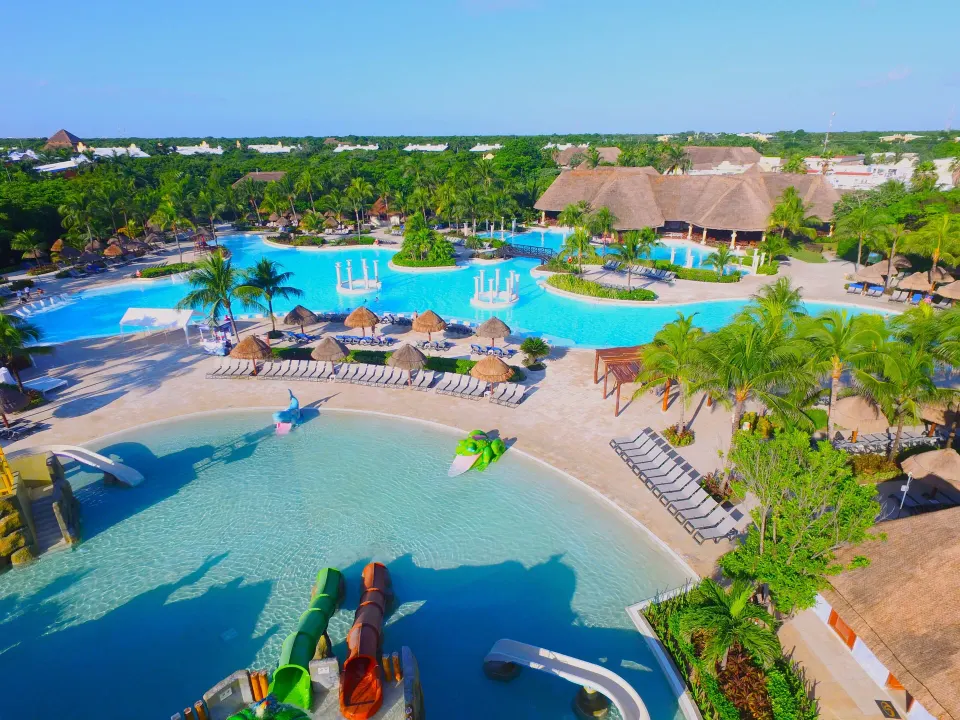 Large resort pool with swim-up areas and thatched-roof palapa at Grand Palladium Colonial Resort & Spa
