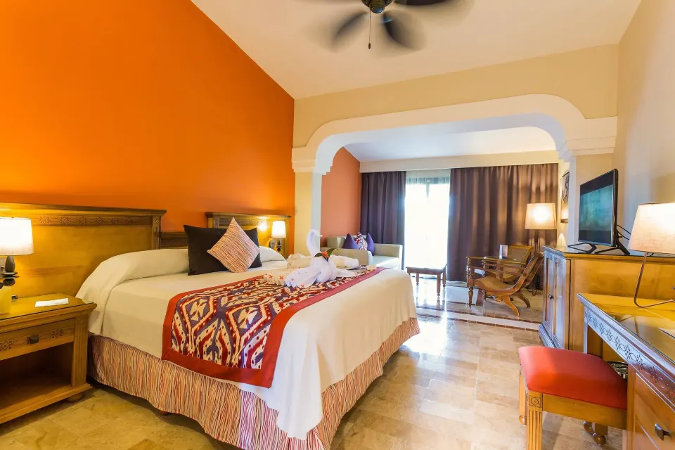 King bed suite with towel art on bed and desk area at Grand Palladium Colonial Resort & Spa