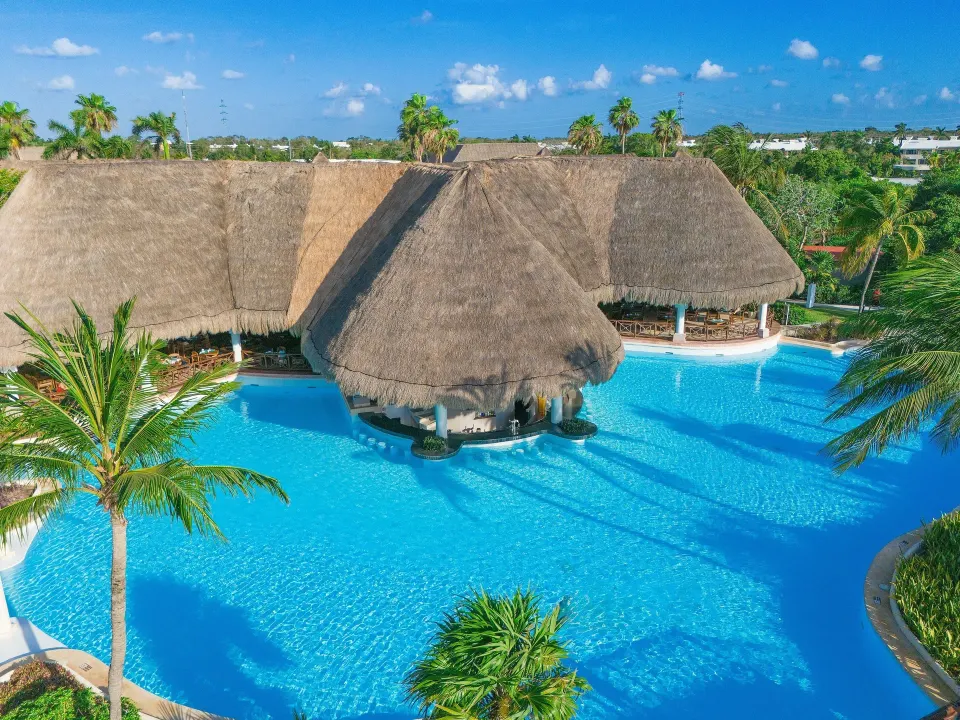 Thatched-roof swim-up bar structure surrounded by the resort pool at Grand Palladium Colonial Resort & Spa
