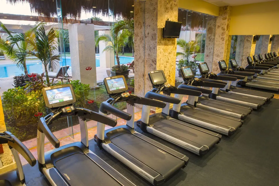 Row of treadmills facing the pool through glass at Grand Palladium Colonial Resort & Spa