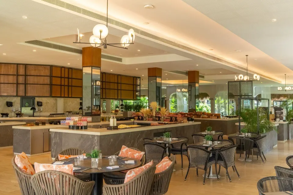 Buffet restaurant interior with wicker chairs and central service counters at Grand Palladium Colonial Resort & Spa