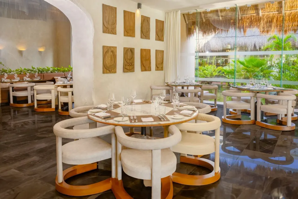 Bright restaurant dining room with round tables and garden view at Grand Palladium Colonial Resort & Spa