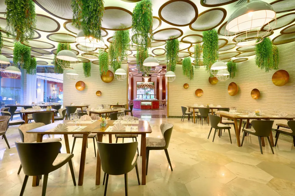 Modern dining room with hanging plants and circular ceiling features at Grand Palladium Colonial Resort & Spa