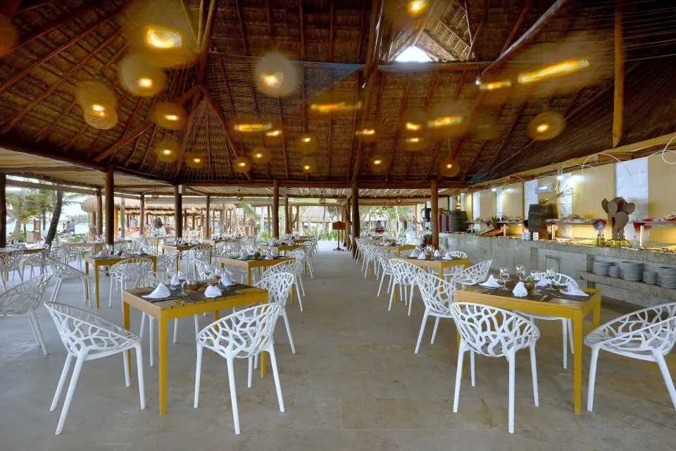 Large open palapa restaurant dining room with many tables at Grand Palladium Colonial Resort & Spa