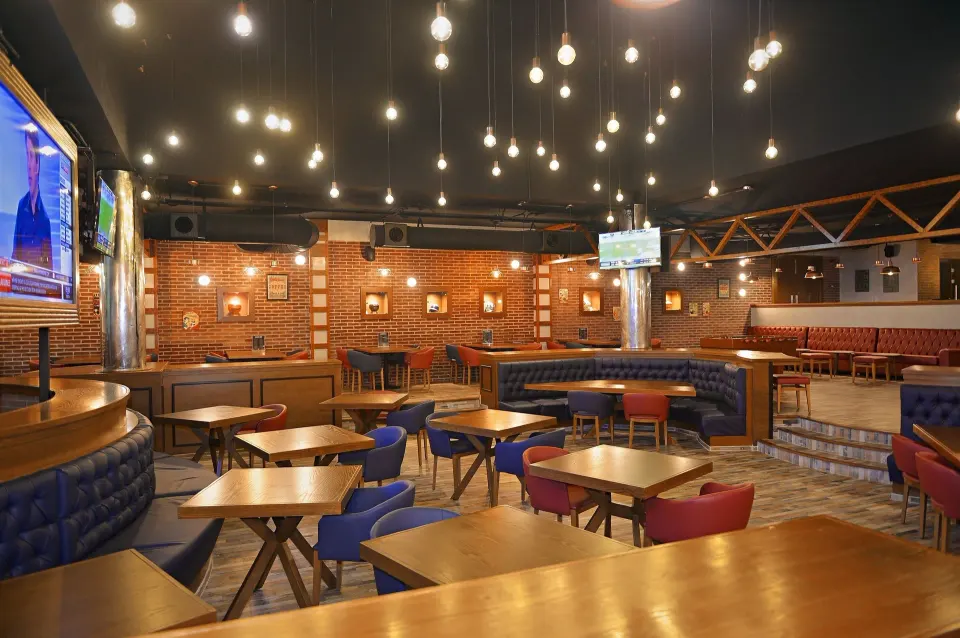 Sports bar interior with TVs, booths and suspended lights at Grand Palladium Colonial Resort & Spa