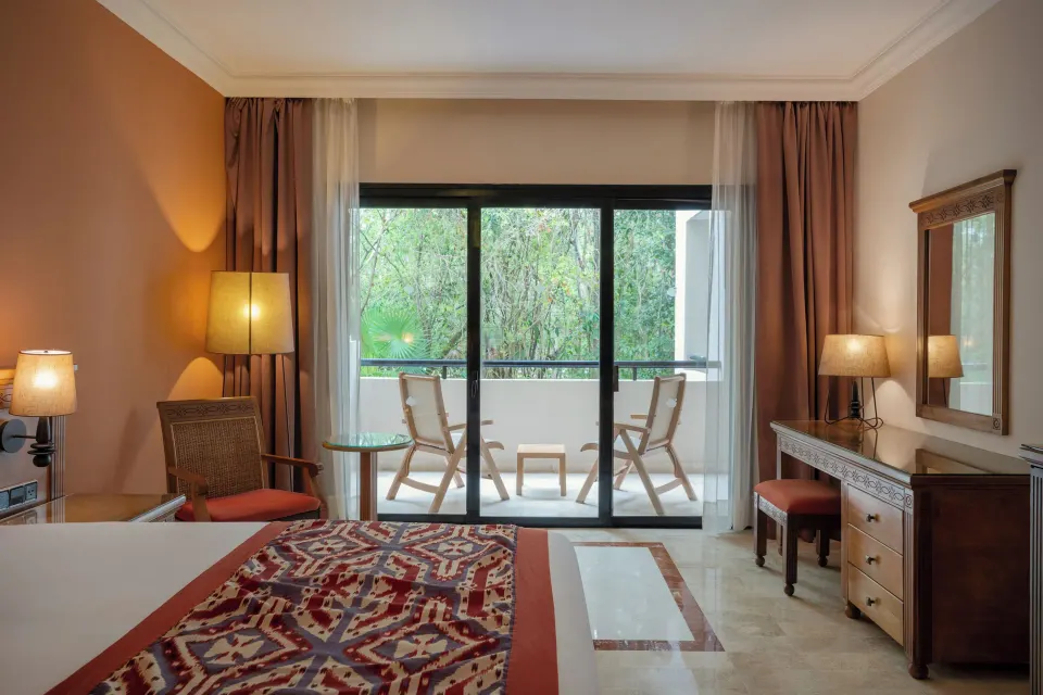 Deluxe Room interior showing bed, desk and balcony at Grand Palladium Colonial Resort & Spa