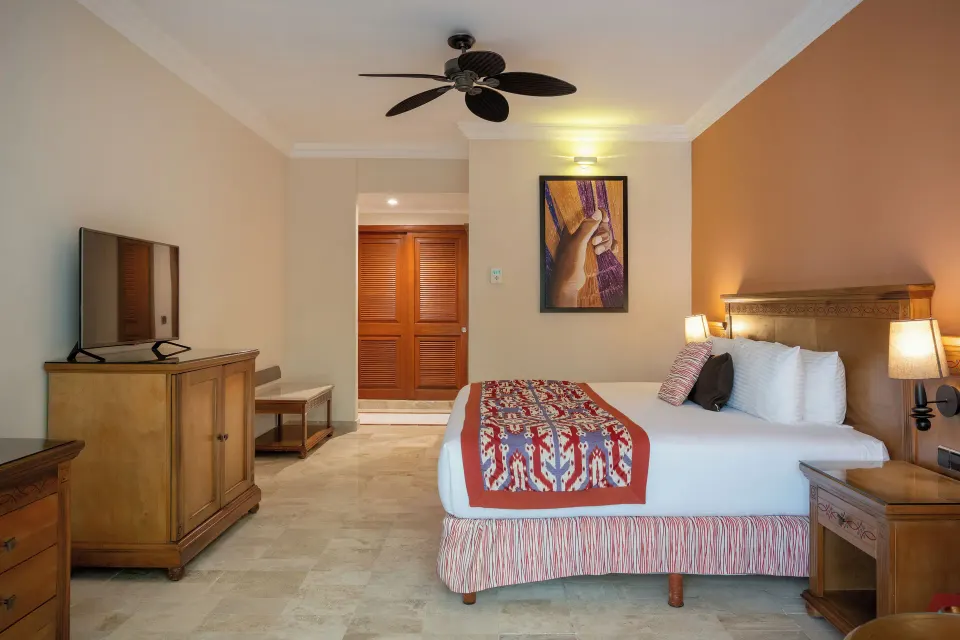 Spacious deluxe guest room with king bed and ceiling fan at Grand Palladium Colonial Resort & Spa