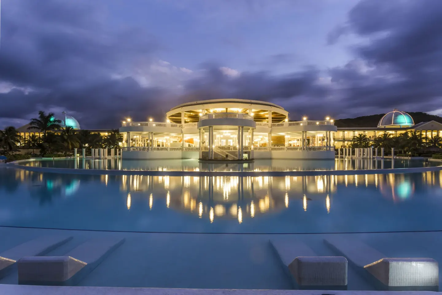 Illuminated resort building reflected in the pool at Grand Palladium Jamaica Resort & Spa.