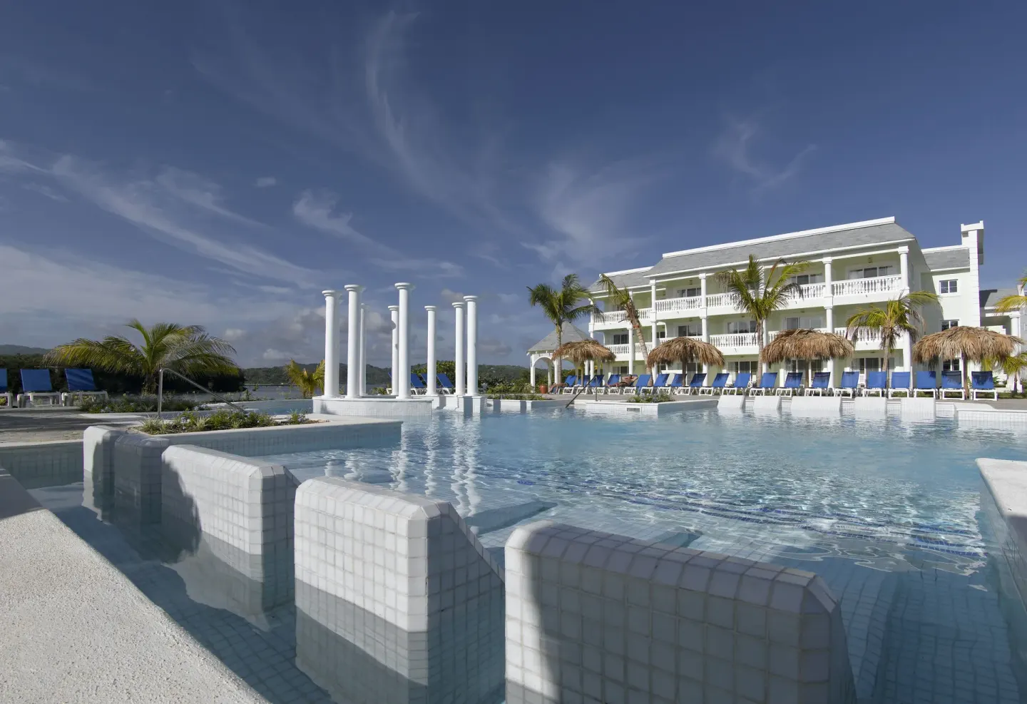 Pool with white columns and resort building at Grand Palladium Jamaica Resort & Spa.