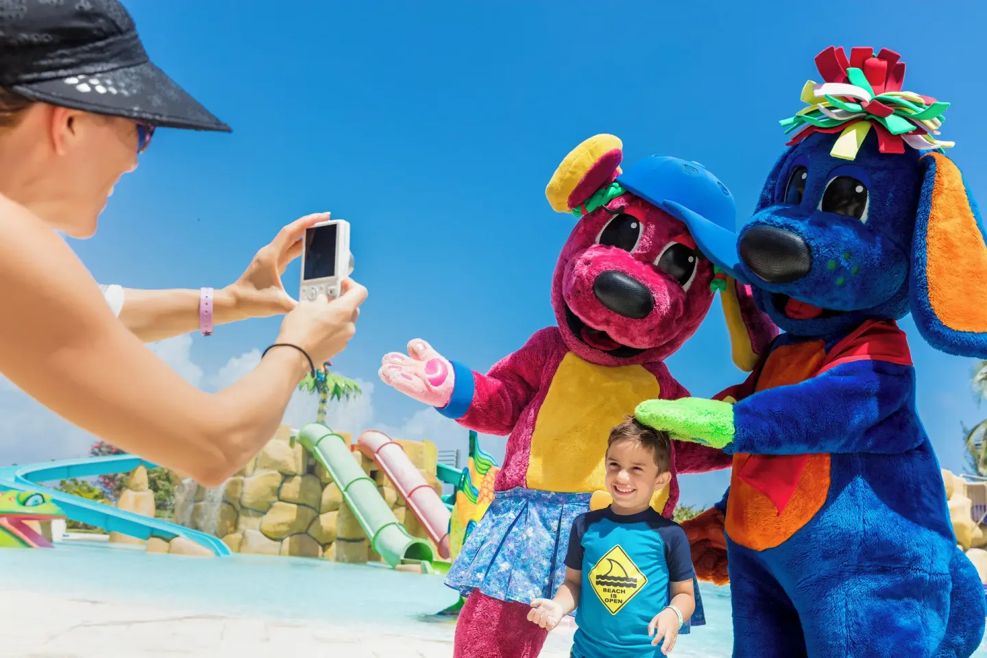 Child posing with colorful mascots by the pool at Grand Palladium Jamaica Resort & Spa.
