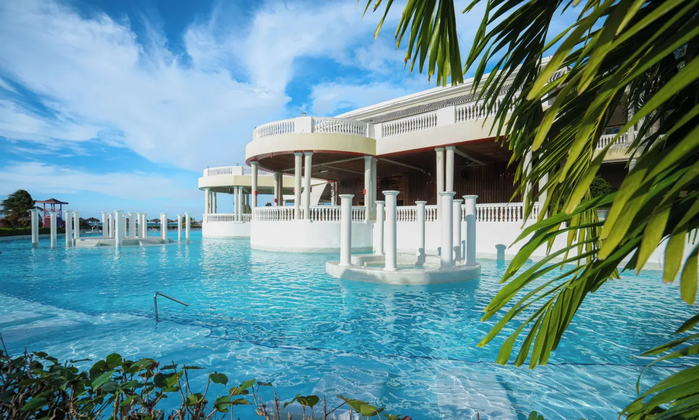 Large pool with white columns and palms at Grand Palladium Jamaica Resort & Spa.