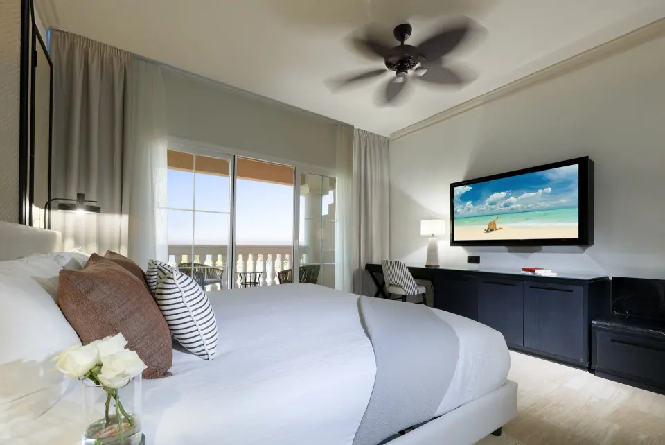 Oceanfront suite king bed with balcony doors at Grand Palladium Jamaica Resort & Spa.
