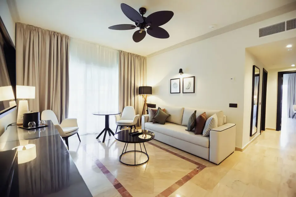 Oceanfront suite lounge with sofa and curtained window at Grand Palladium Jamaica Resort & Spa.