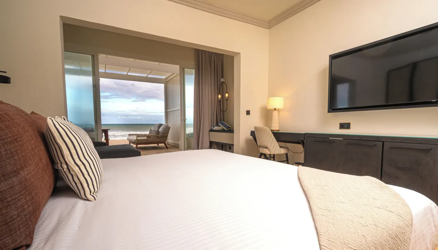 Suite king bed with TV and oceanfront patio at Grand Palladium Jamaica Resort & Spa.