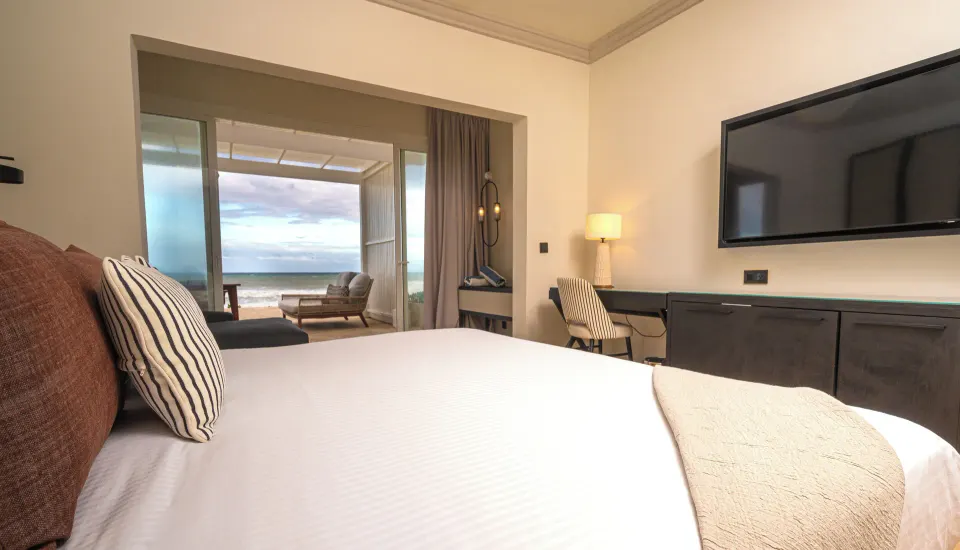 Suite king bed with TV and oceanfront patio at Grand Palladium Jamaica Resort & Spa.