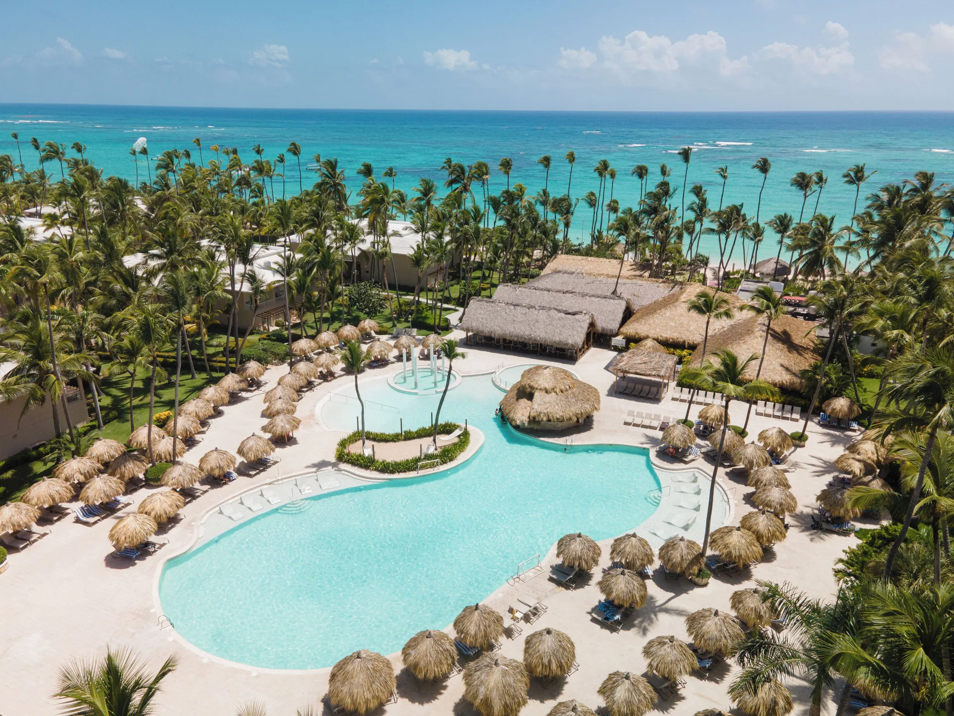 Aerial pool and palm-lined beach at Grand Palladium Palace Resort Spa & Casino.