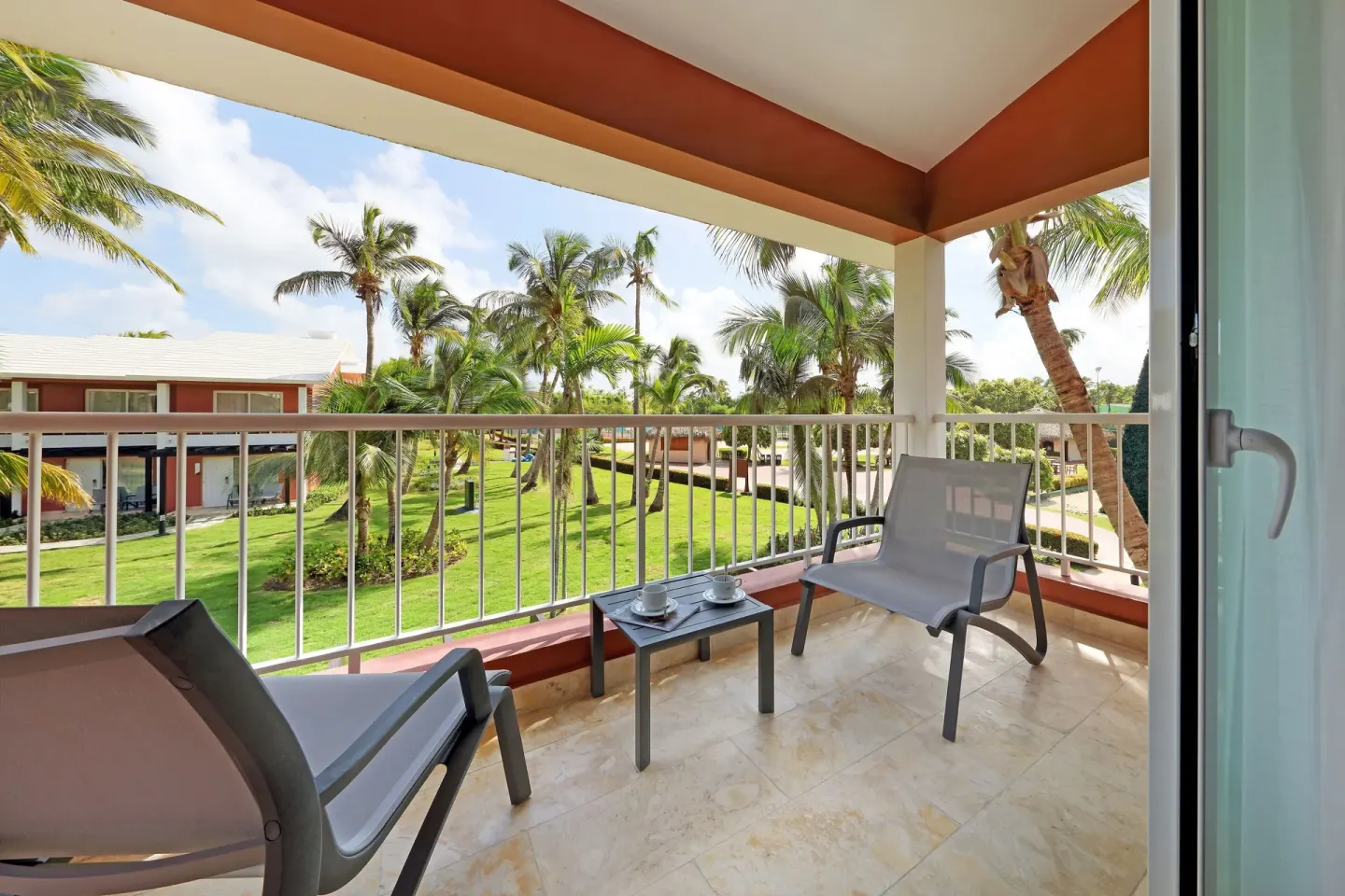 Furnished balcony overlooking palms and lawns at Grand Palladium Palace Resort Spa & Casino.