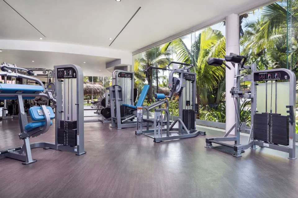 Gym machines beside tropical windows at Grand Palladium Palace Resort Spa & Casino.