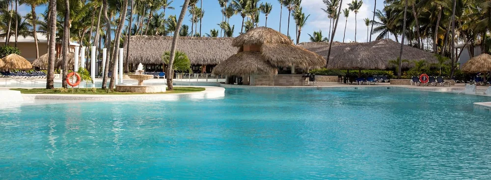 Large pool with thatched swim-up area at Grand Palladium Palace Resort Spa & Casino.