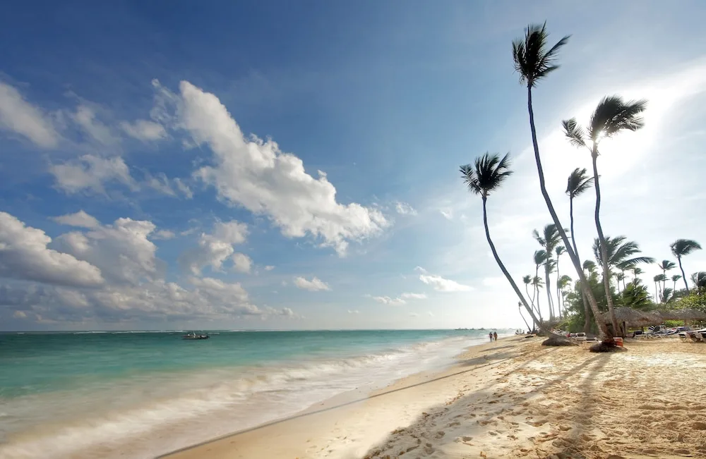 Palm-lined beach and surf at Grand Palladium Palace Resort Spa & Casino.