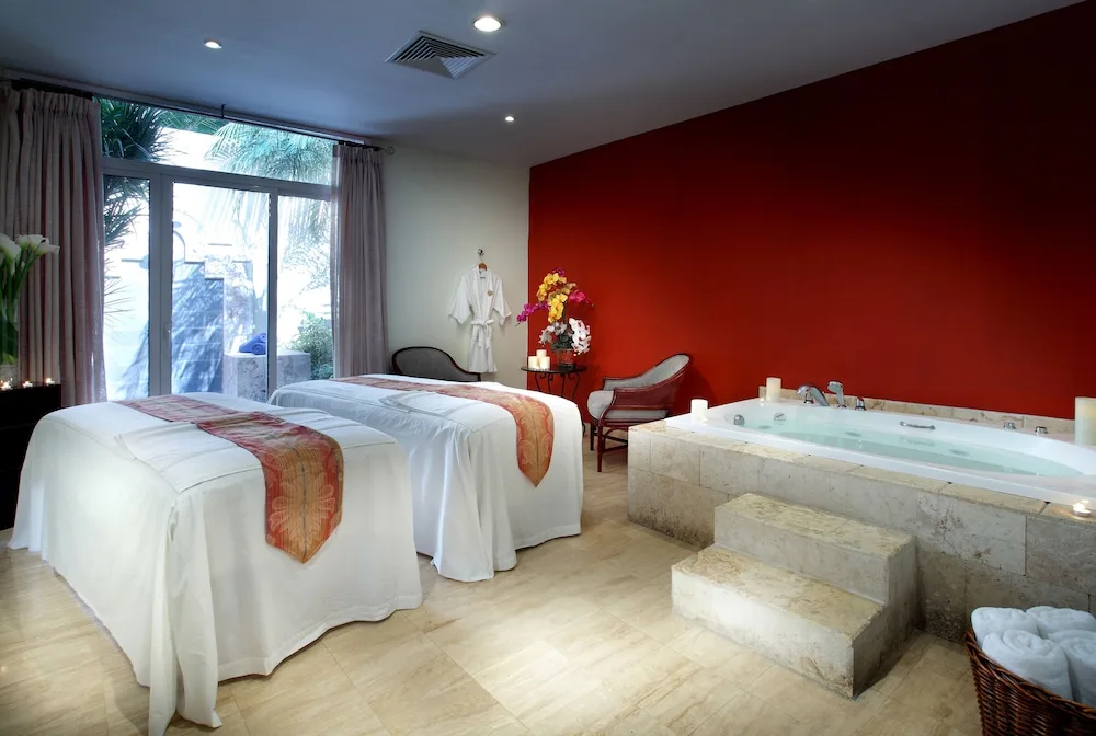 Spa treatment room with two massage tables and a whirlpool tub at Grand Palladium Palace Resort Spa & Casino.