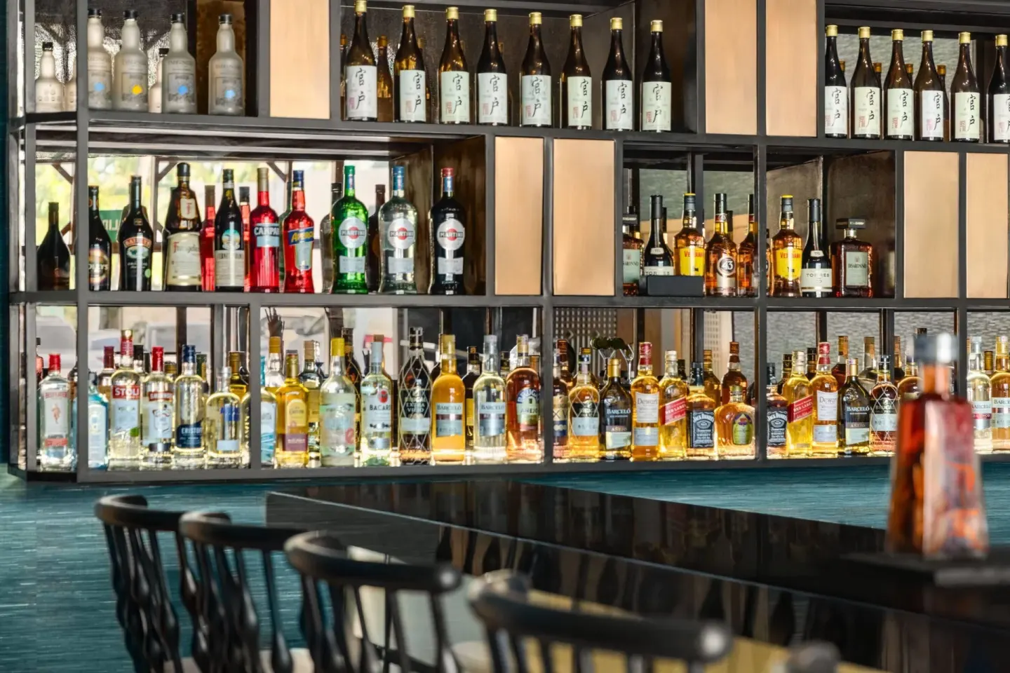 Back bar shelves with bottles and counter seating at Grand Palladium Palace Resort Spa & Casino.