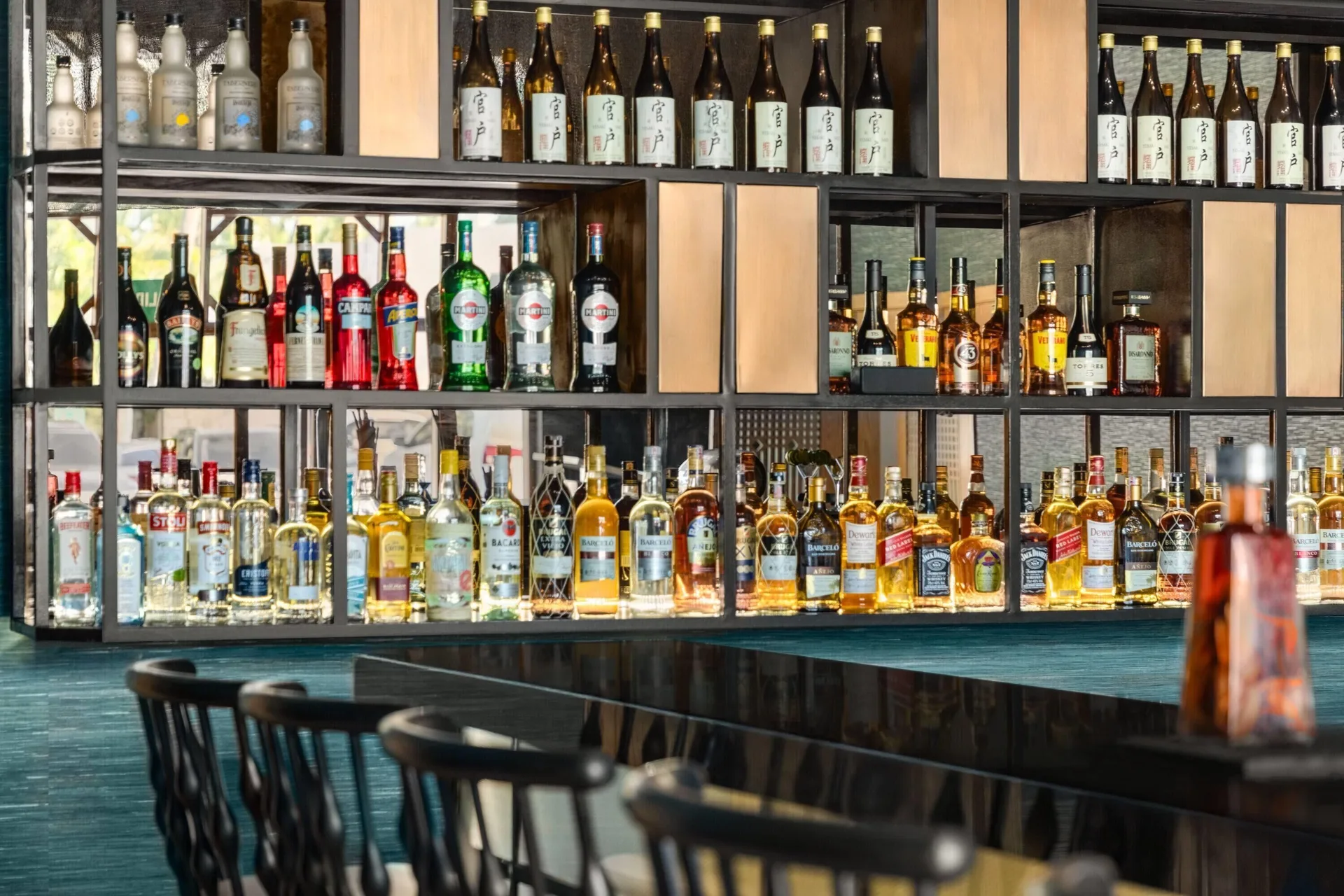 Back bar shelves with bottles and counter seating at Grand Palladium Palace Resort Spa & Casino.