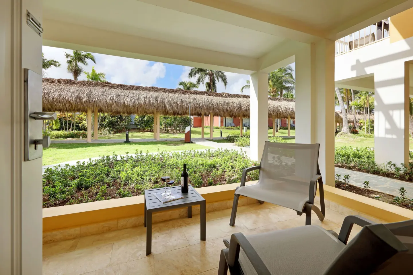 Covered patio with chairs and garden walkway at Grand Palladium Punta Cana Resort & Spa.